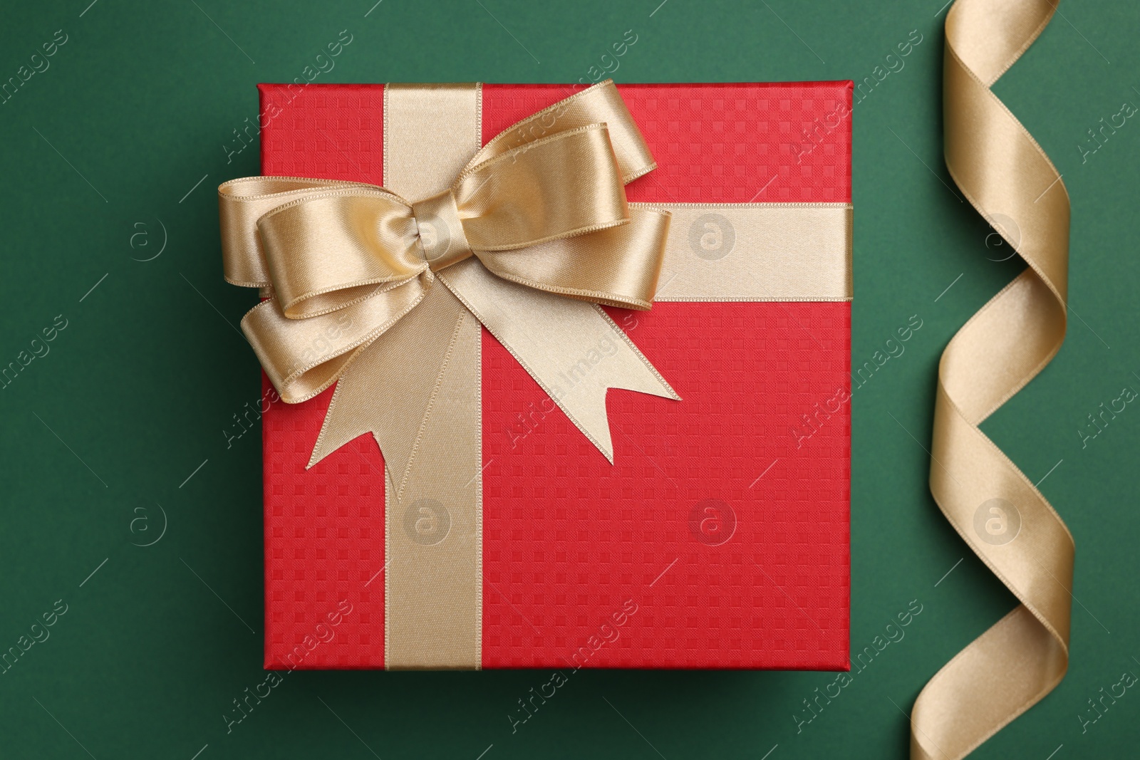 Photo of Beautiful red gift box with bow and ribbons on green background, flat lay