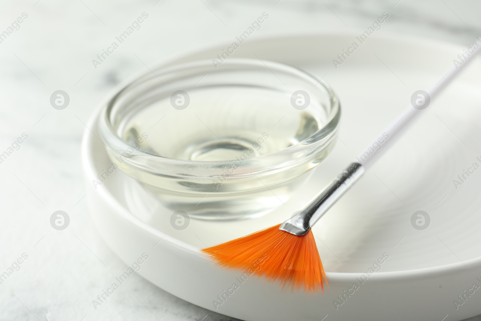 Photo of Bowl of chemical peel and brush on white table, closeup. Peeling procedure