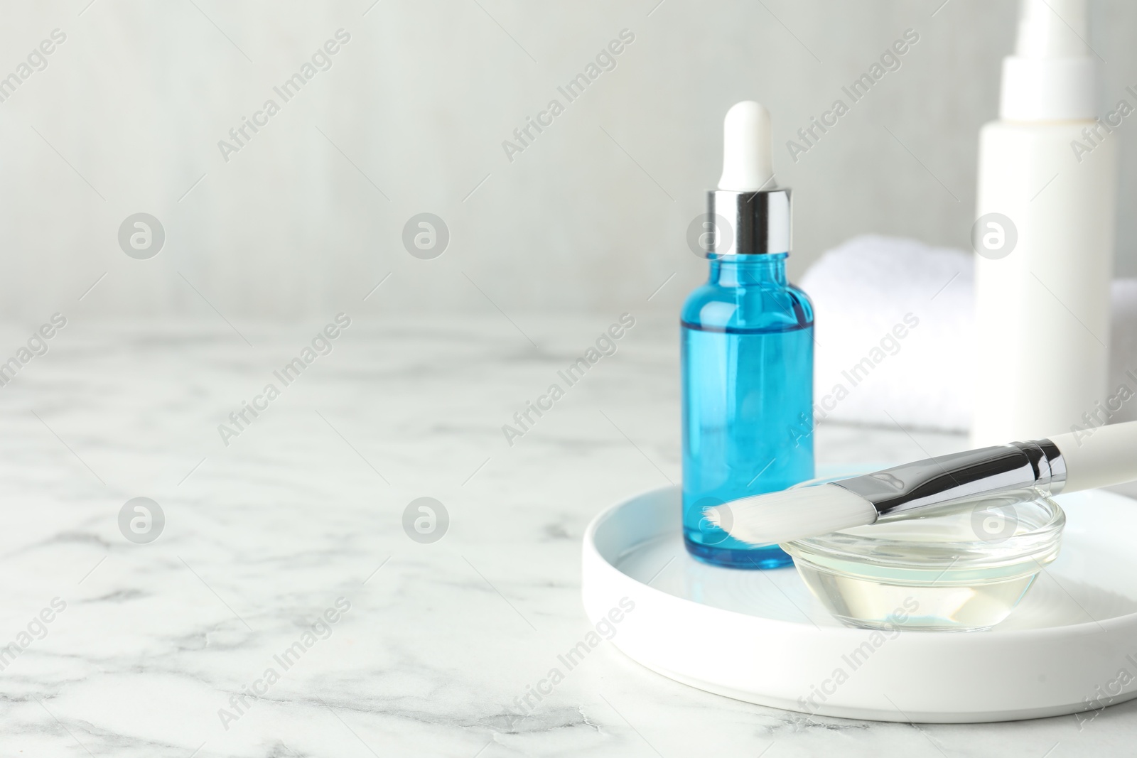 Photo of Bottle of chemical peel, bowl with liquid and brush on white marble table, space for text. Peeling procedure