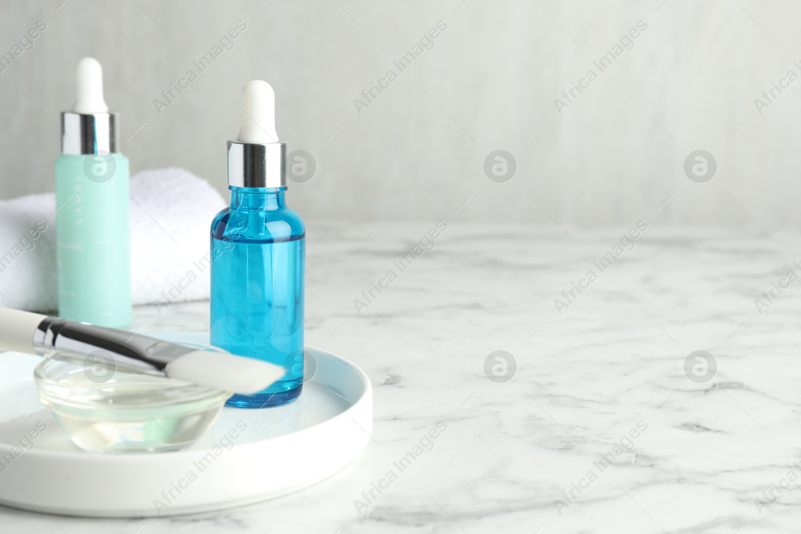 Photo of Bottles of chemical peel, bowl with liquid and brush on white marble table, space for text. Peeling procedure