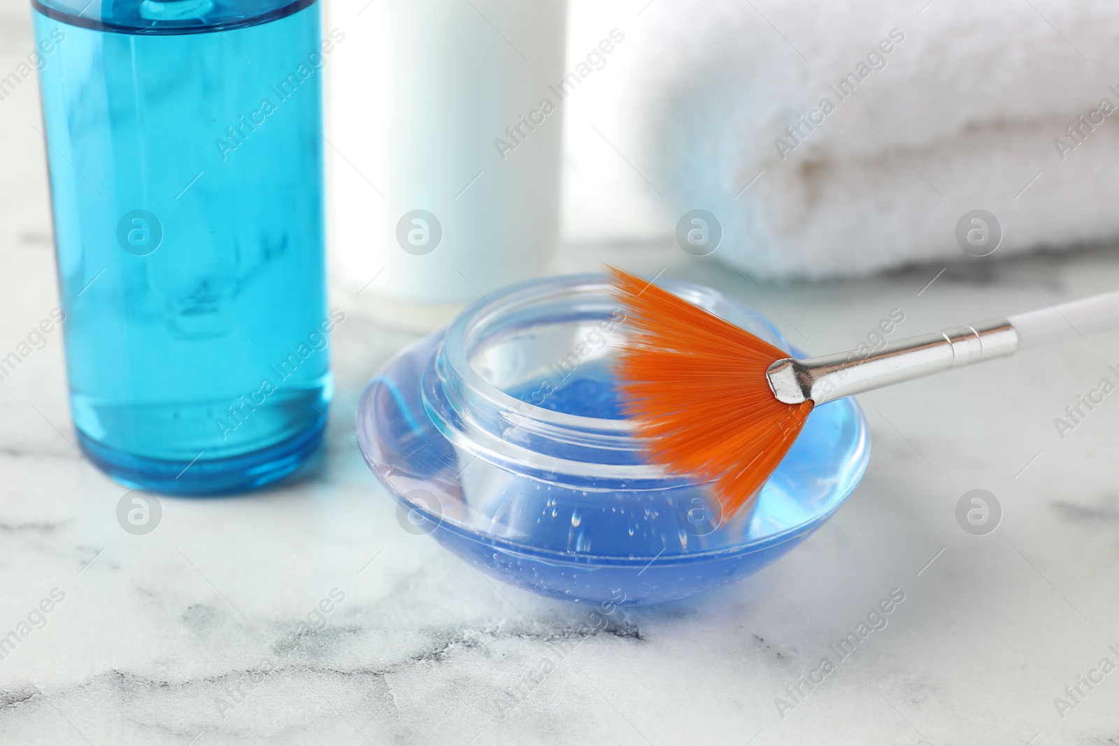 Photo of Chemical peel in bowl and brush on white marble table, closeup. Peeling procedure