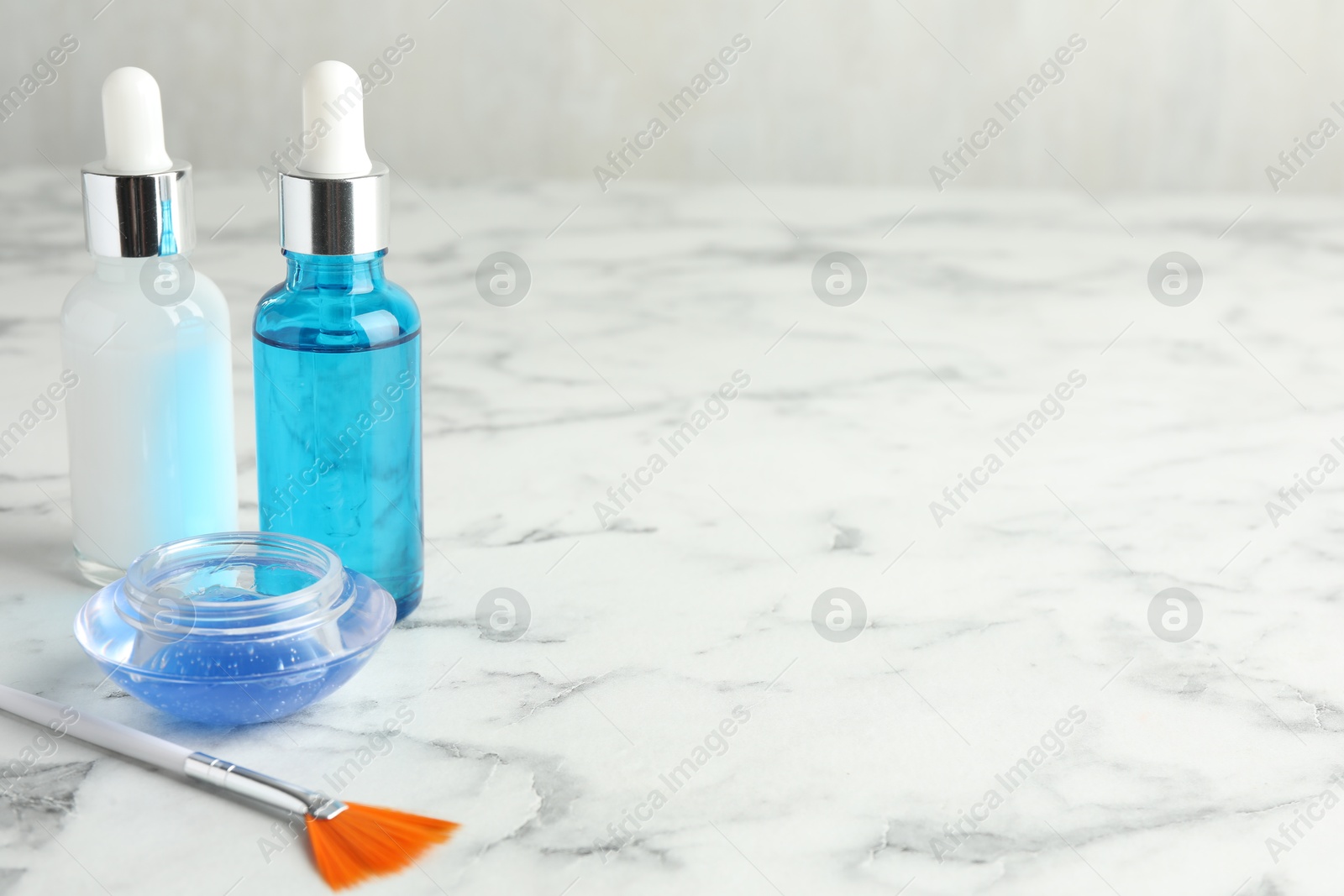 Photo of Bottles of chemical peel, bowl with liquid and brush on white marble table, space for text. Peeling procedure