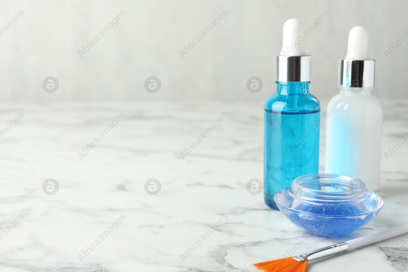 Photo of Bottles of chemical peel, bowl with liquid and brush on white marble table, space for text. Peeling procedure