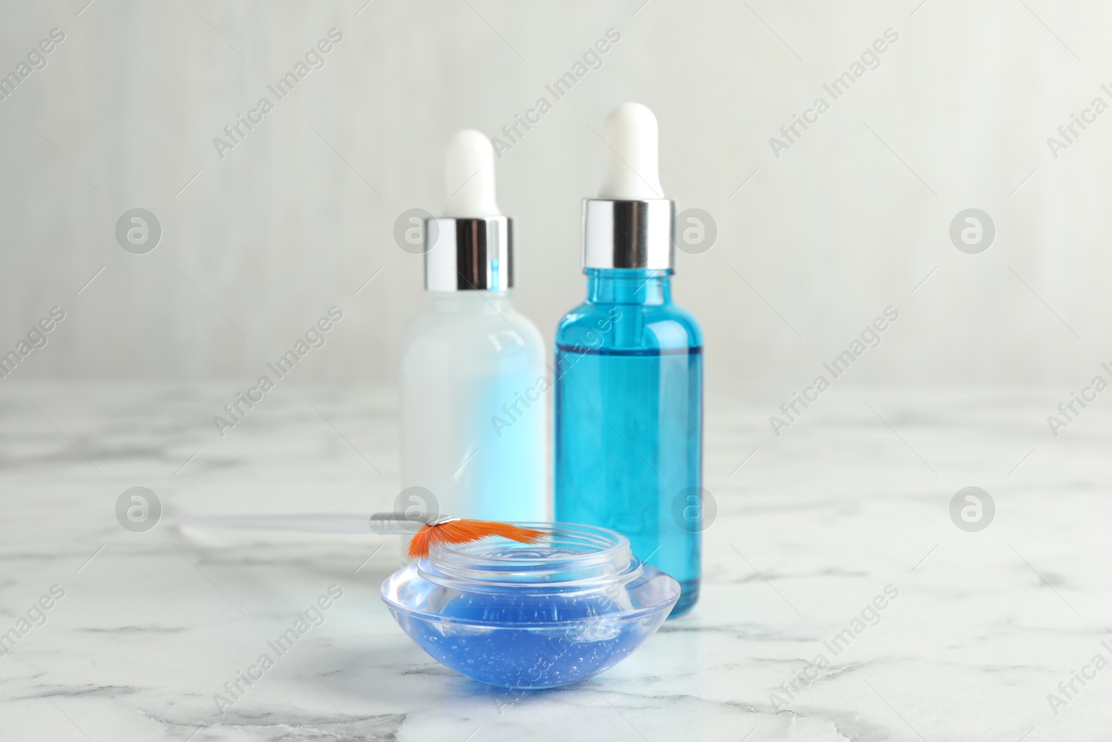 Photo of Bottles of chemical peel, bowl with liquid and brush on white marble table. Peeling procedure