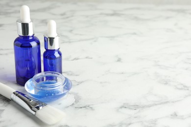 Photo of Bottles of chemical peel, bowl with liquid and brush on white marble table, space for text. Peeling procedure