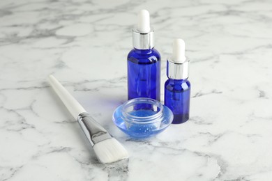 Photo of Bottles of chemical peel, bowl with liquid and brush on white marble table. Peeling procedure