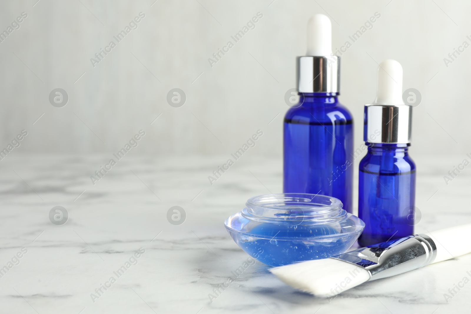 Photo of Bottles of chemical peel, bowl with liquid and brush on white marble table, space for text. Peeling procedure