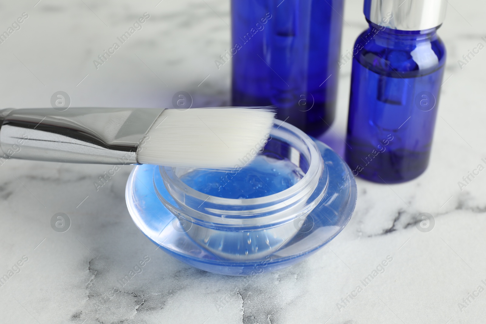 Photo of Chemical peel with brush on white marble table, closeup. Peeling procedure