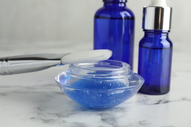 Photo of Chemical peel with brush on white marble table, closeup. Peeling procedure