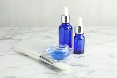 Photo of Bottles of chemical peel, bowl with liquid and brush on white marble table. Peeling procedure