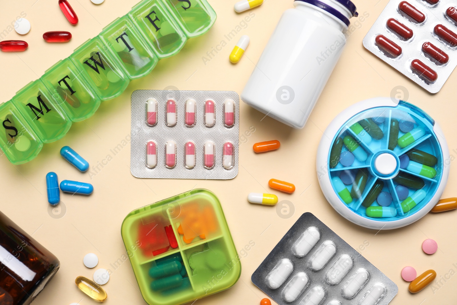 Photo of Different pills, organizers and medical jars on beige background, flat lay