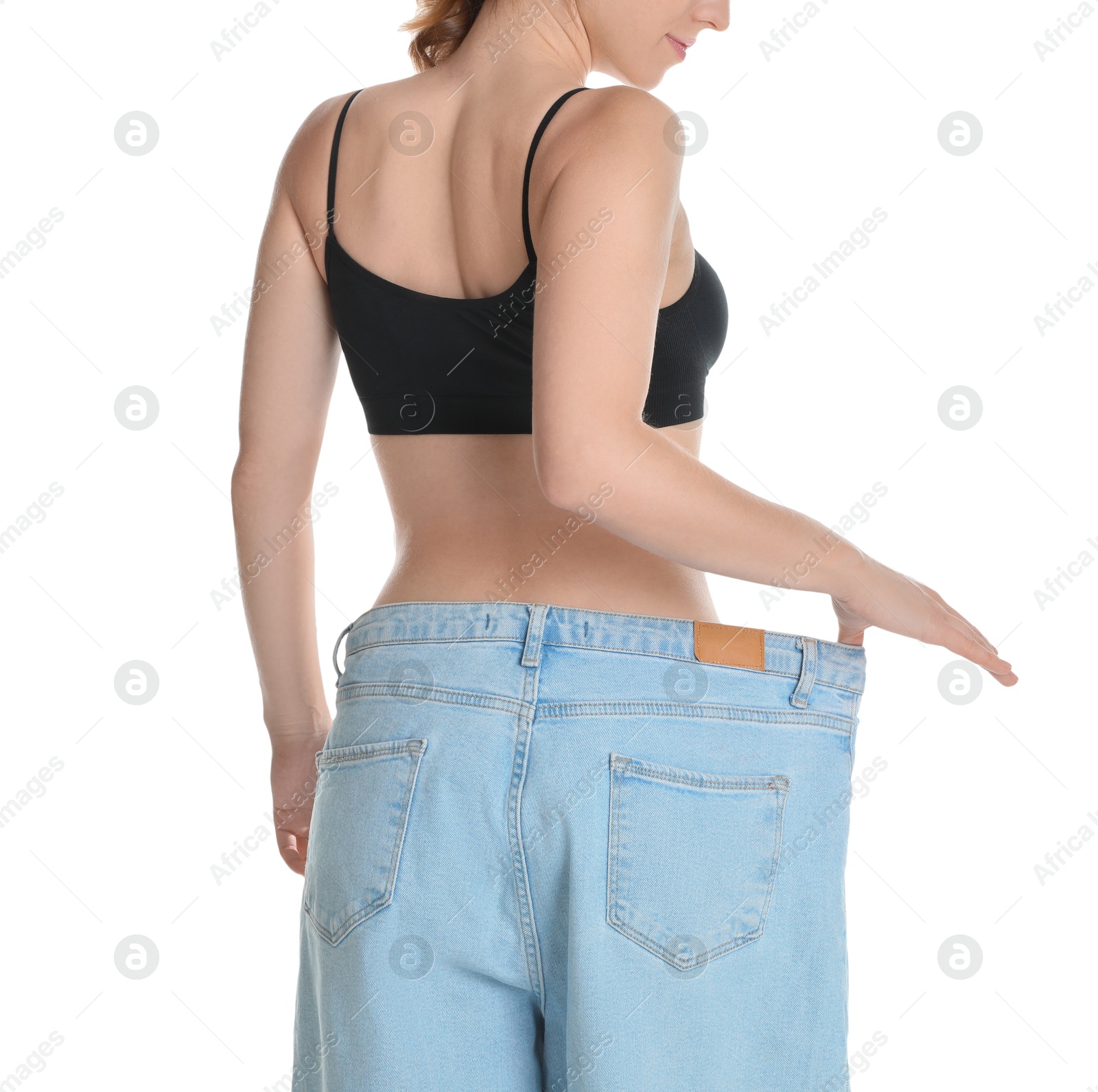 Photo of Woman in big jeans showing her slim body on white background, closeup