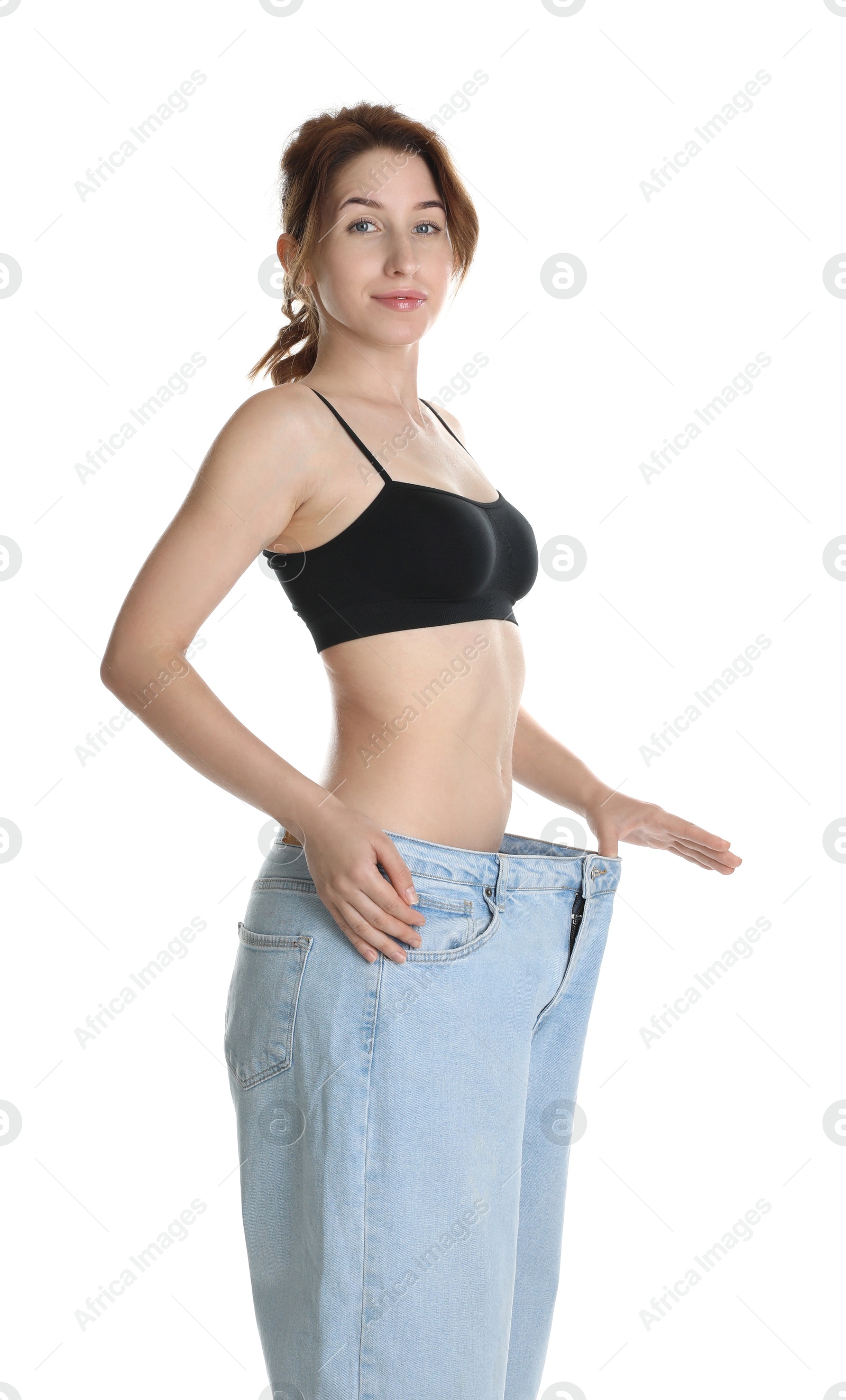 Photo of Woman in big jeans showing her slim body on white background