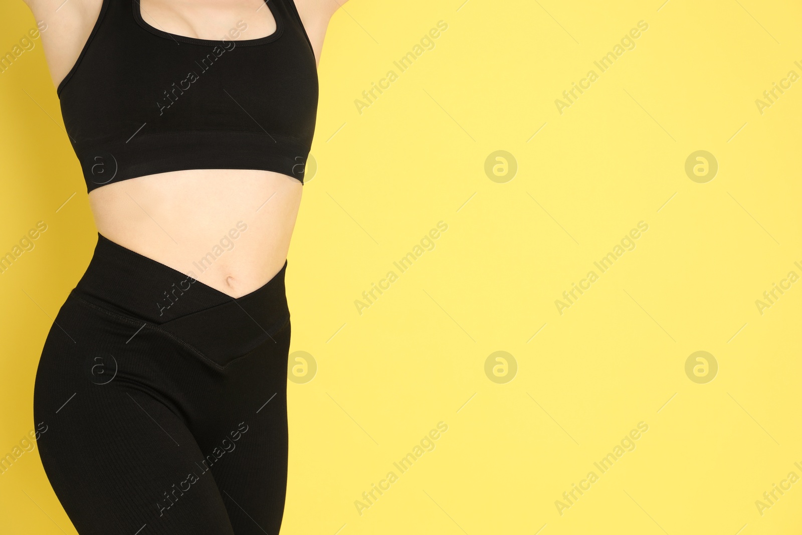 Photo of Woman with slim body posing on yellow background, closeup. Space for text