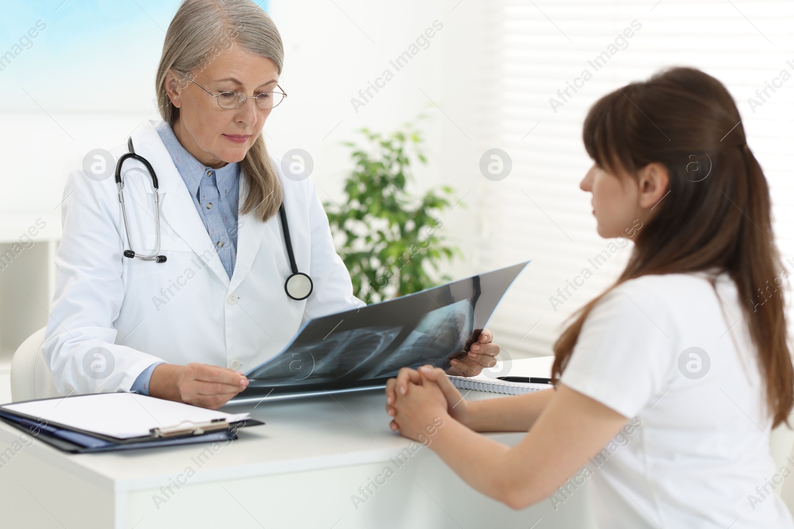 Photo of Lung disease. Doctor with chest x-ray consulting patient in clinic