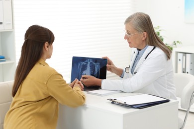 Photo of Lung cancer. Doctor showing chest x-ray on laptop to her patient in clinic