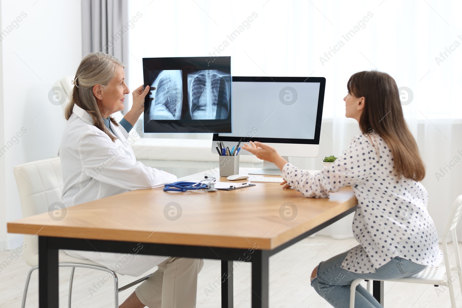 Photo of Lung disease. Doctor showing chest x-ray to her patient in clinic