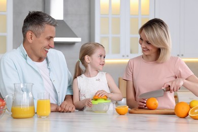 Happy family making juice at white marble table in kitchen