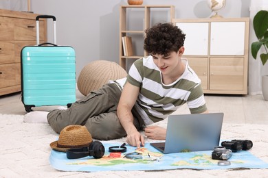 Travel blogger using laptop and map for planning trip at home
