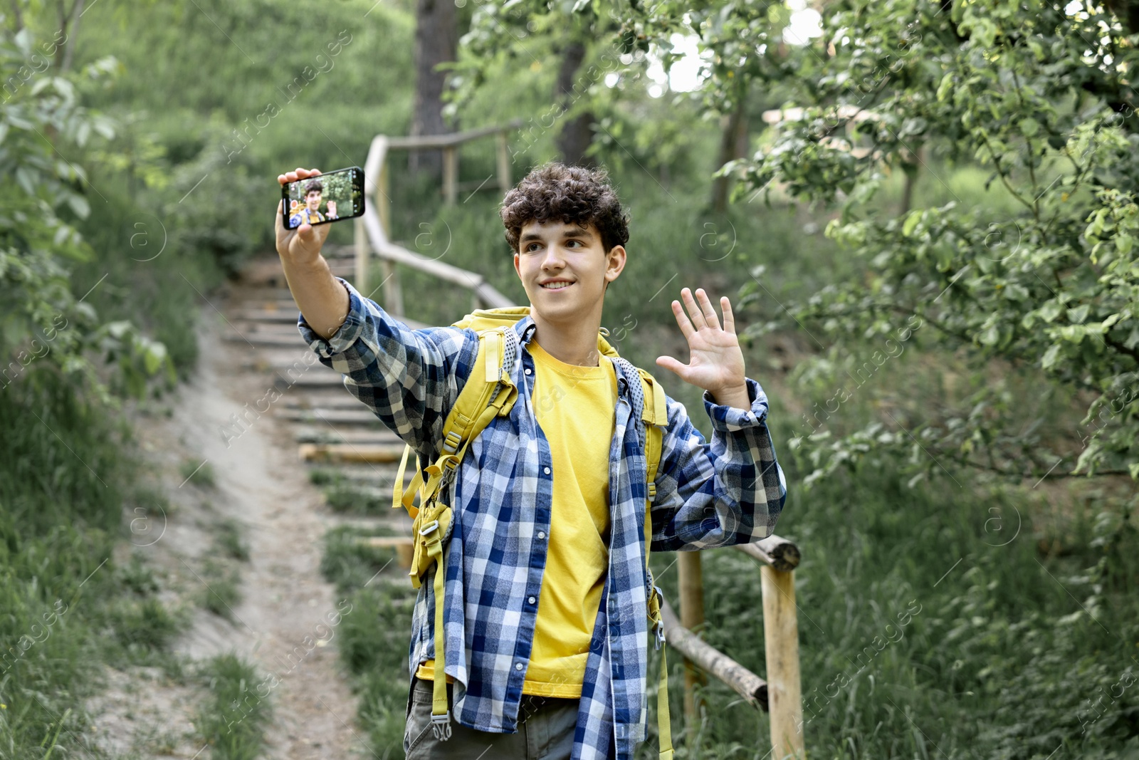 Photo of Smiling travel blogger with smartphone streaming outdoors