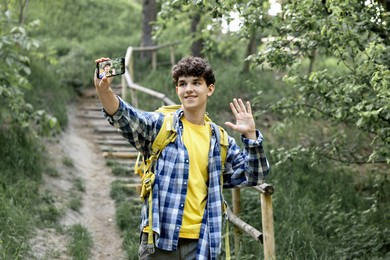 Photo of Smiling travel blogger with smartphone streaming outdoors