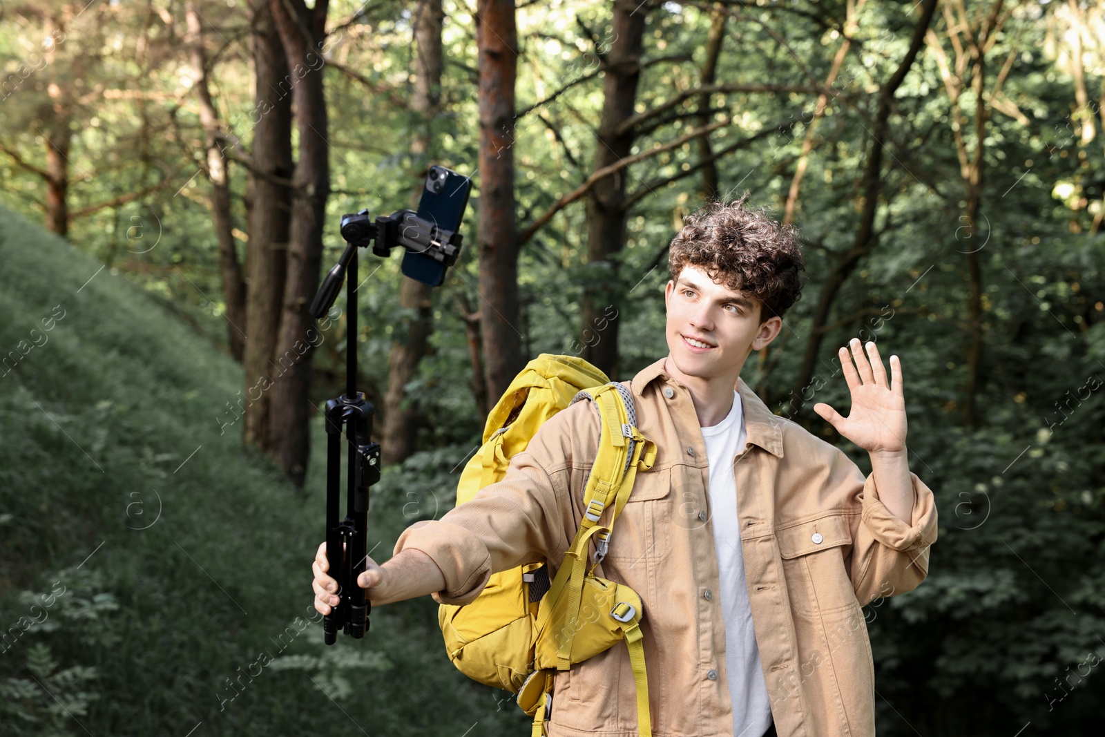 Photo of Travel blogger with smartphone and tripod streaming outdoors