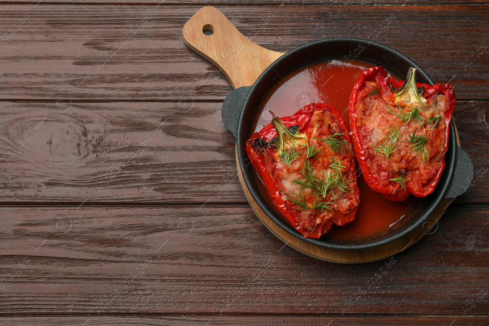 Photo of Tasty stuffed peppers in dish on wooden table, top view. Space for text