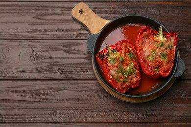 Photo of Tasty stuffed peppers in dish on wooden table, top view. Space for text