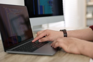 Photo of Programmer working with laptop at desk in office, closeup