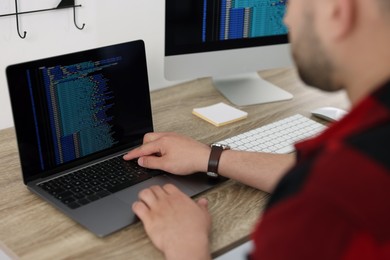 Programmer working with laptop at desk in office, closeup