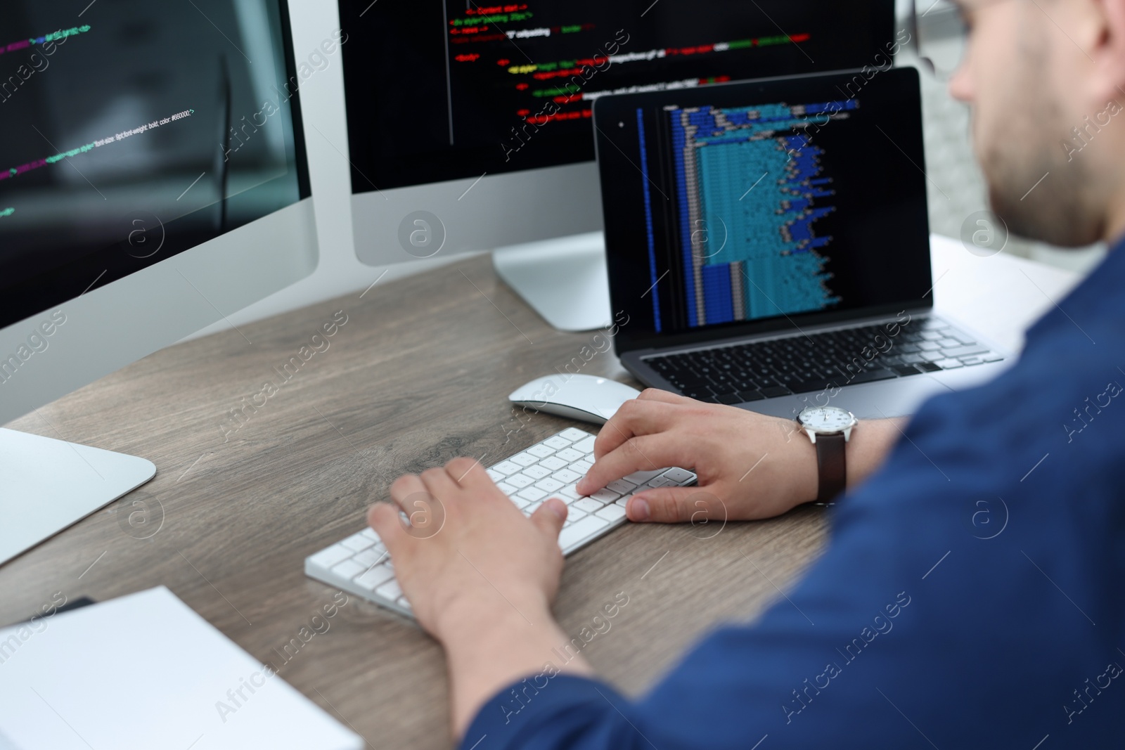 Photo of Programmer working with computer at desk in office, closeup