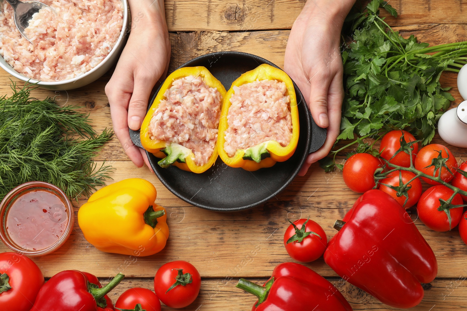 Photo of Woman making stuffed peppers with ground meat at wooden table, top view