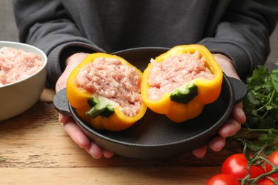 Woman making stuffed peppers with ground meat at wooden table, closeup
