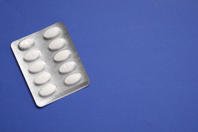 Antibiotic pills in blister on blue background, top view. Space for text