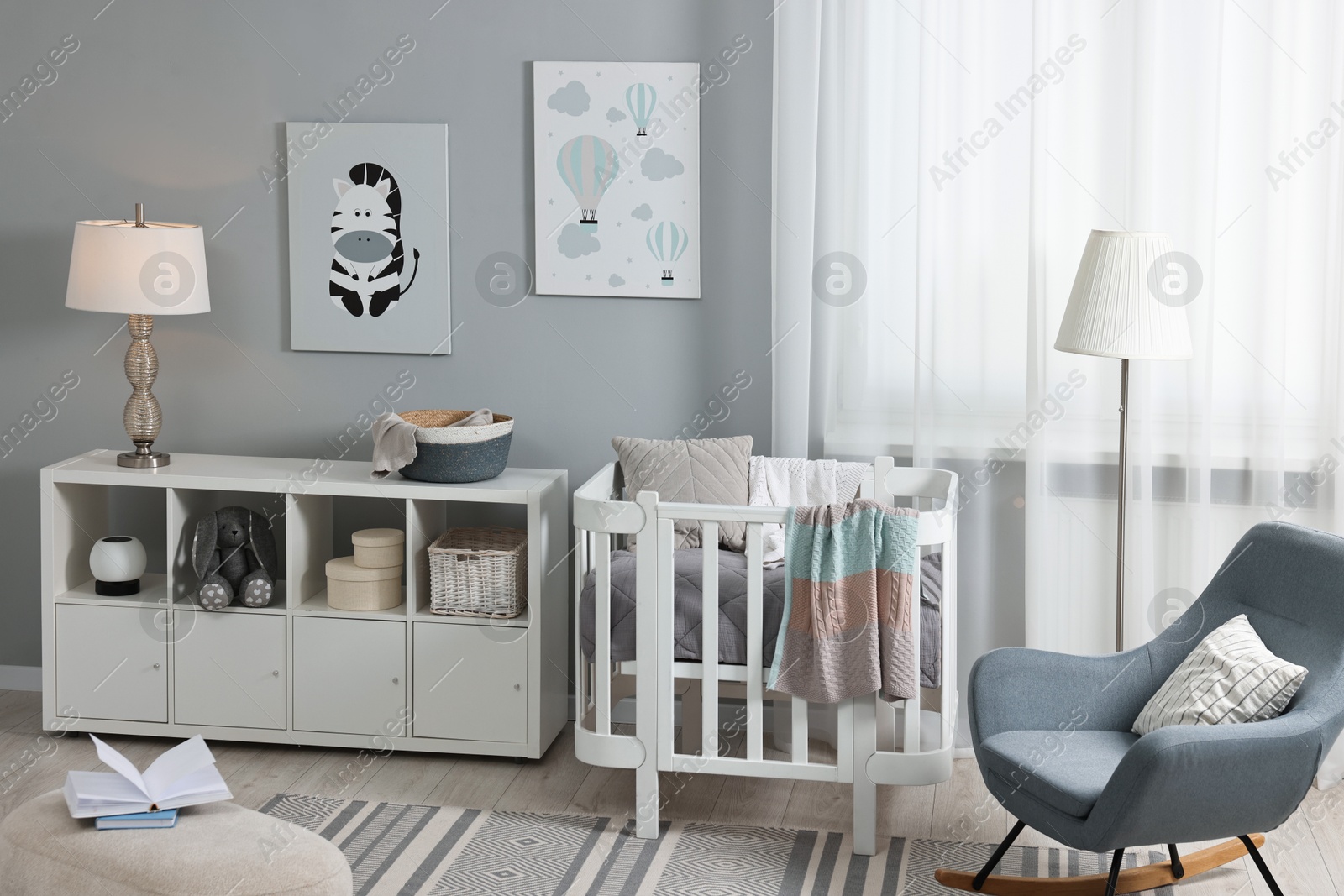 Photo of Newborn baby room interior with stylish furniture, comfortable crib and pictures of on wall