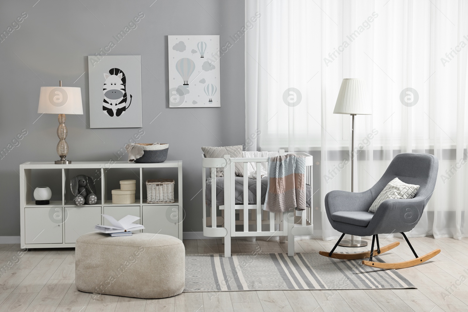 Photo of Newborn baby room interior with stylish furniture, comfortable crib and pictures of on wall