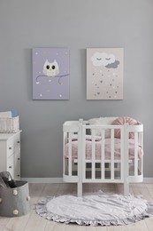 Photo of Newborn baby room interior with stylish furniture, comfortable crib and pictures of on wall