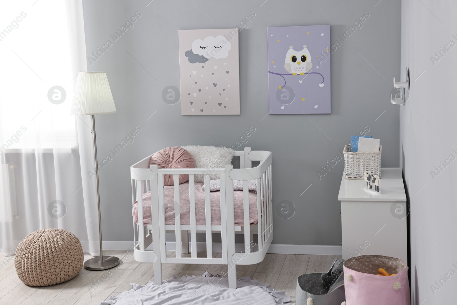 Photo of Newborn baby room interior with stylish furniture, comfortable crib and pictures of on wall