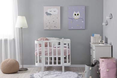 Photo of Newborn baby room interior with stylish furniture, comfortable crib and pictures of on wall