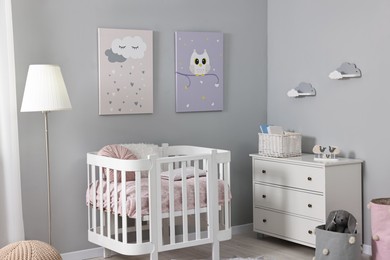 Photo of Newborn baby room interior with stylish furniture, comfortable crib and pictures of on wall