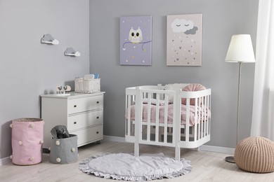 Photo of Newborn baby room interior with stylish furniture, comfortable crib and pictures of on wall