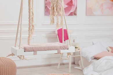 Photo of Cute child's room interior with swing and beautiful pictures of on wall