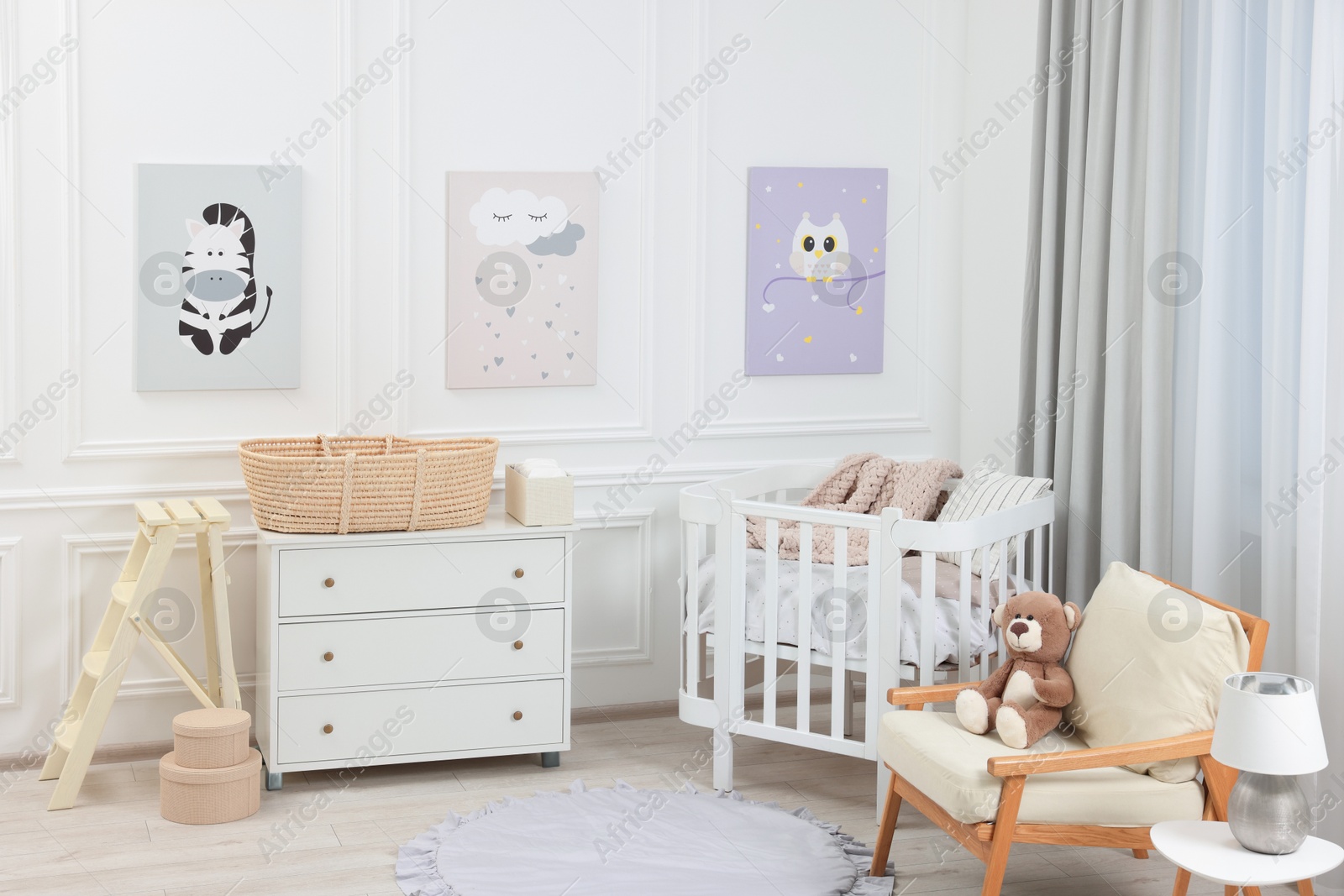 Photo of Newborn baby room interior with stylish furniture, comfortable crib and pictures of on wall