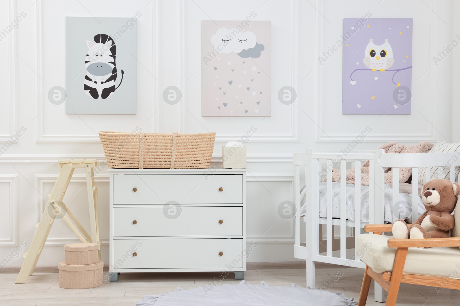 Photo of Newborn baby room interior with stylish furniture, comfortable crib and pictures of on wall