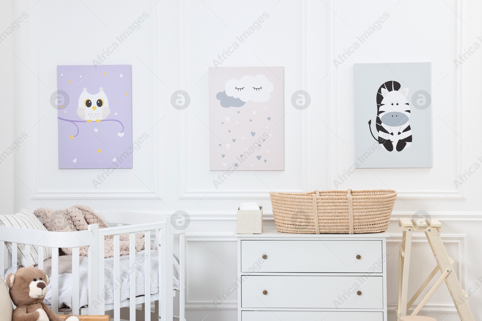 Photo of Newborn baby room interior with stylish furniture, comfortable crib and pictures of on wall