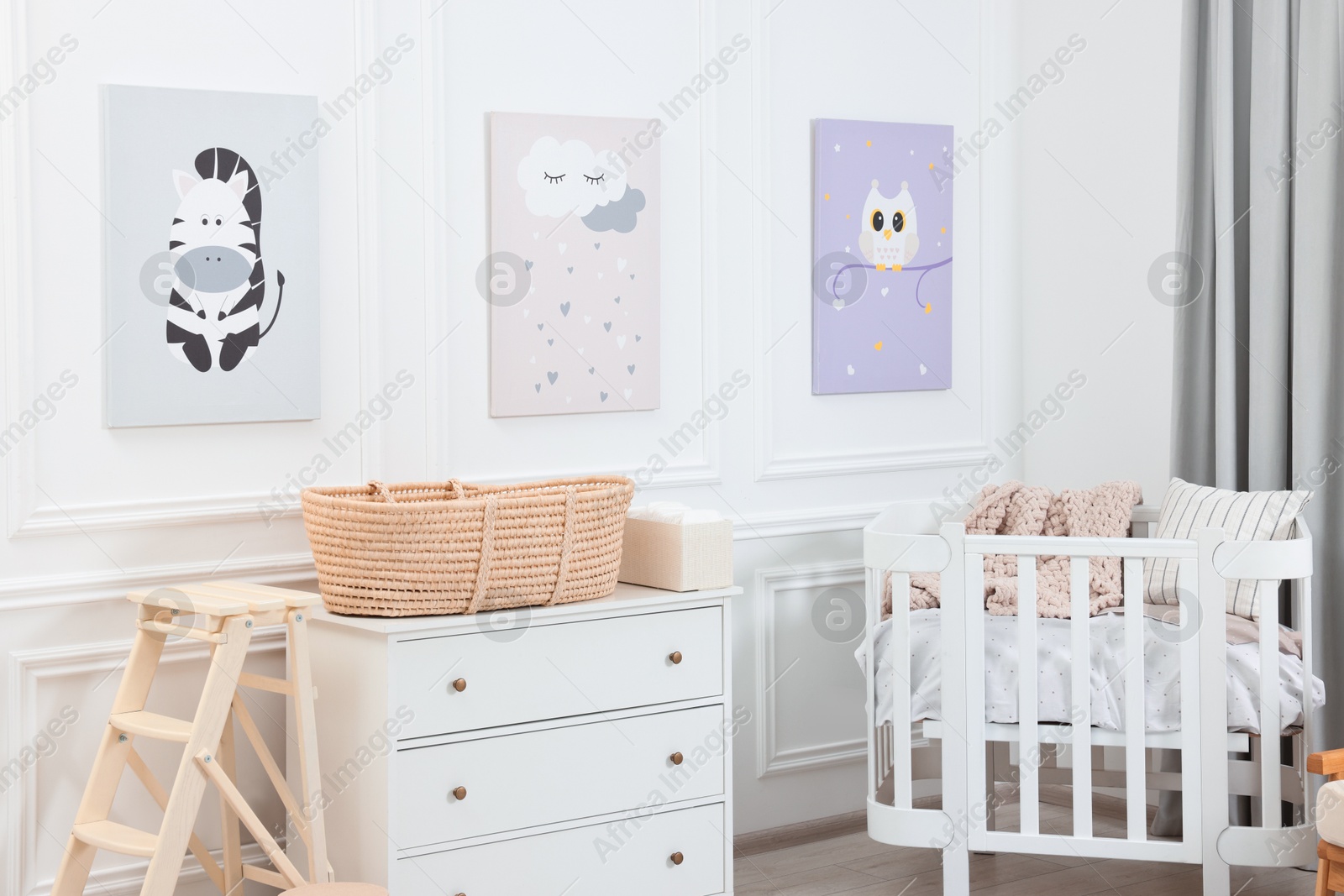 Photo of Newborn baby room interior with stylish furniture, comfortable crib and pictures of on wall