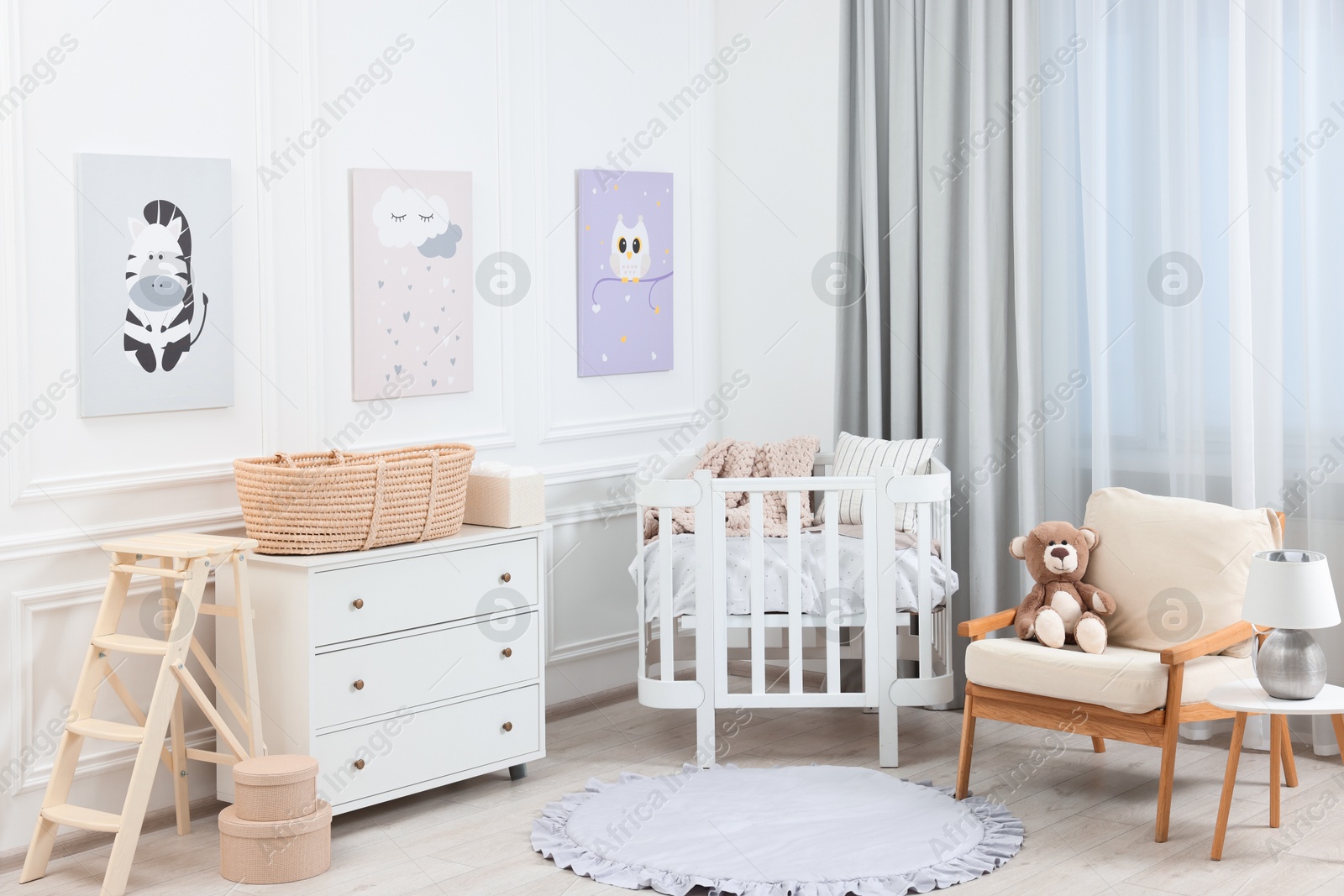 Photo of Newborn baby room interior with stylish furniture, comfortable crib and pictures of on wall