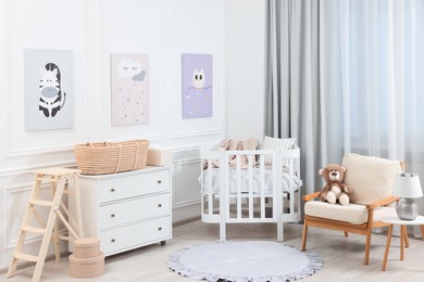 Photo of Newborn baby room interior with stylish furniture, comfortable crib and pictures of on wall