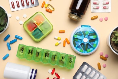 Different pills, organizers and medical jars on beige background, flat lay