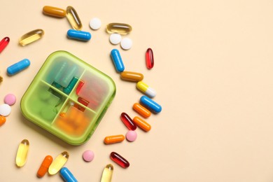 Different pills and organizer on beige background, flat lay. Space for text